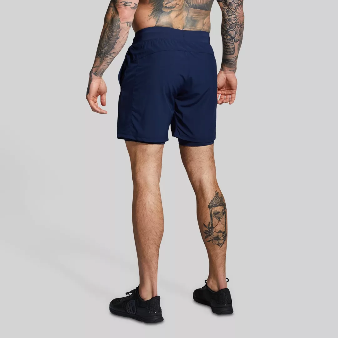 Mann med mørkeblå trenings-shorts med lommer og innertights. Innertightsen har lomme på én side.