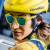 Kvinne med sykkelhjelm som har på seg gule solbriller fra Goodr. Glassene er reflekterende. Det står goodr på siden av innfatningen.