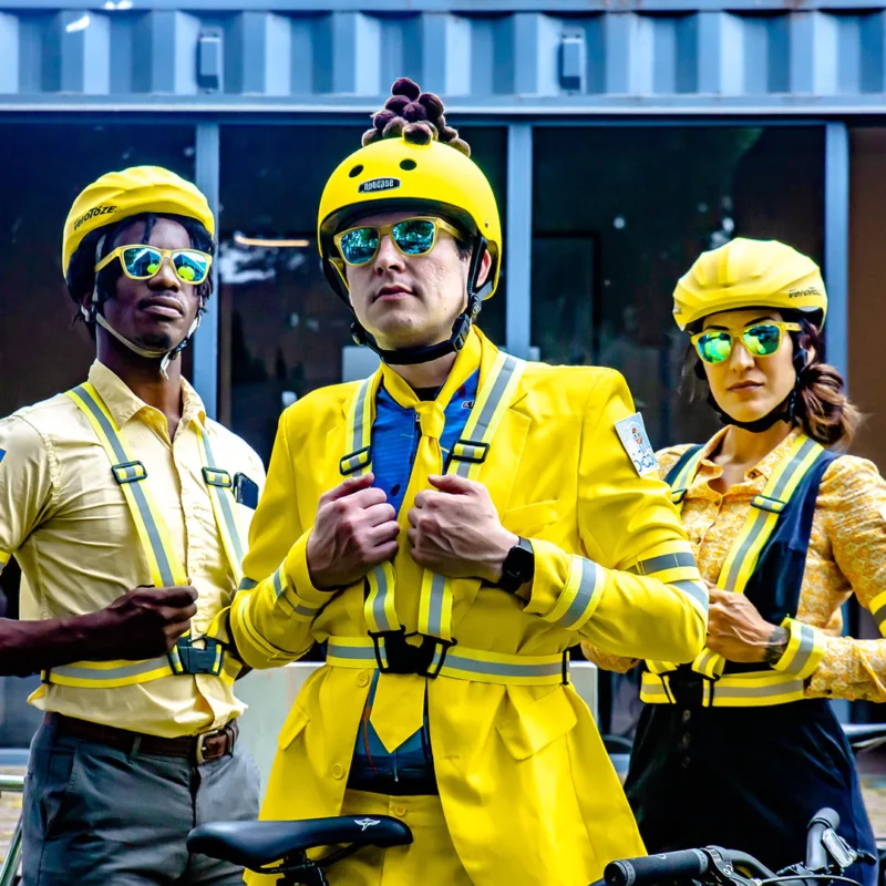 Tre personer i gule klær som Mann med sykkelhjelm som har på seg gule solbriller fra Goodr.