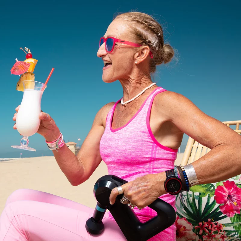 Kvinne med manual i den ene hånden, en drink i den andre og rosa solbriller fra Goodr, Flamingos on a booze cruise