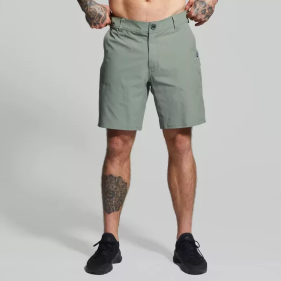Beina til en mann i grønn shorts i teknisk stoff vendt med fronten mot kameraet. Shortsen har en lomme på hver side. Den har glidelås og knapp, samt hemper til belte.
