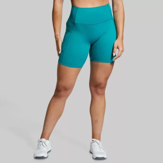 Beina til en dame i grønn shorts i teknisk stoff vendt mot kameraet. Shortsen har lomme på siden. Den er høy i livet.