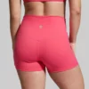 Beina til en dame i rosa shorts i teknisk stoff som står med ryggen mot kameraet. Shortsen er høy i livet.