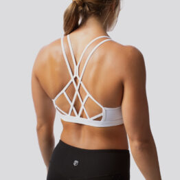 Dame i hvit sports-bh i teknisk stoff som står med ryggen mot kameraet. Sports-bhen har tynne stropper som går på kryss og tvers på ryggen.