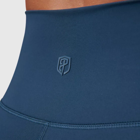 Korsryggen til en dame i blå tights i teknisk stoff. Det er Born Primitives logo i den samme fargen som tightsen på korsryggen.
