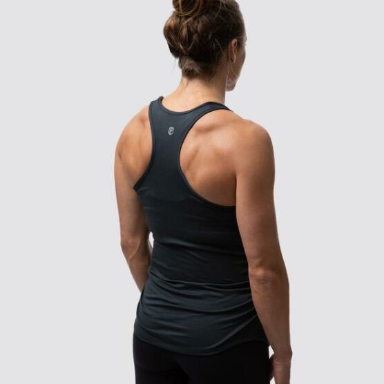 Gravid dame i sort treningssinglet i teknisk stoff med ryggen skrått mot. Det er racerback rygg og brede stropper over skuldrene.