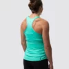 Gravid dame i mintgrønn treningssinglet i teknisk stoff med ryggen skrått mot. Det er racerback rygg og brede stropper over skuldrene.