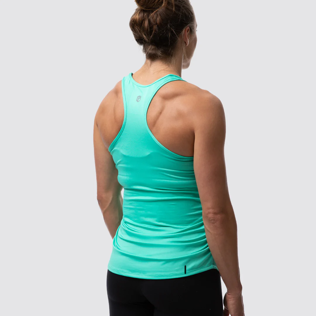 Gravid dame i mintgrønn treningssinglet i teknisk stoff med ryggen skrått mot. Det er racerback rygg og brede stropper over skuldrene.