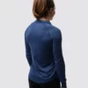 En gravid dame i blå genser i teknisk stoff som står med ryggen mot kameraet.