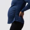 En gravid dame i blå genser i teknisk stoff som står med siden mot kameraet.