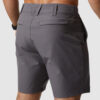 Beina til en mann i mørkegrå shorts i polyester med ryggen mot kameraet. Shortsen har en lomme på hver side av rumpa.