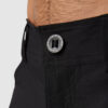 Beina til en mann i sort bukse i teknisk stoff vendt med fronten mot kameraet. Den har glidelås og knapp, samt hemper til belte.