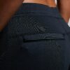 Kvinne iført sort treningsbukse. Detaljbilde av lomme bak