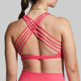 Dame i rosa sports-bh i teknisk stoff med ryggen mot kameraet. Sports-bhen har 4 stropper på hver side som krysser hverandre litt over skulderbladene.