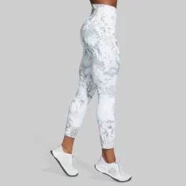 Beina til en dame som står med side mot kameraet. Hun har på seg en Eccentric legging som er lys grå og hvitmønstret.