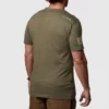 Mann iført militærgrønn t-skjorte avbildet bakfra . På høyre skulder/øvre del av rygg vises fire ulike smålogoer/ikoner i hvit farge.
