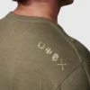 Mann iført militærgrønn t-skjorte. På høyre skulder/øvre del av rygg vises fire ulike smålogoer/ikoner i hvit farge.