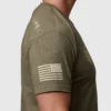 Mann avbildet fra siden, i en militærgrønn T-skjorte. På overarmen vises det amerikanske flagget i hvitt.