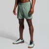 Mann avbildet fra livet og ned iført en grønn shorts, og hvite joggesko