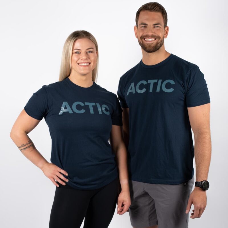 actic tee, Mann og kvinne avbildet forfra, iført mørk blå t-skjorte med ACTIC skrevet i blått over brystet