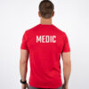 Mann avbildet bakfra iført en rød t-skjorte med skriften MEDIC skrevet i hvit midt på bak.