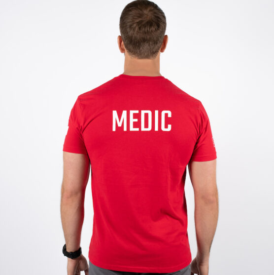 Mann avbildet bakfra iført en rød t-skjorte med skriften MEDIC skrevet i hvit midt på bak.