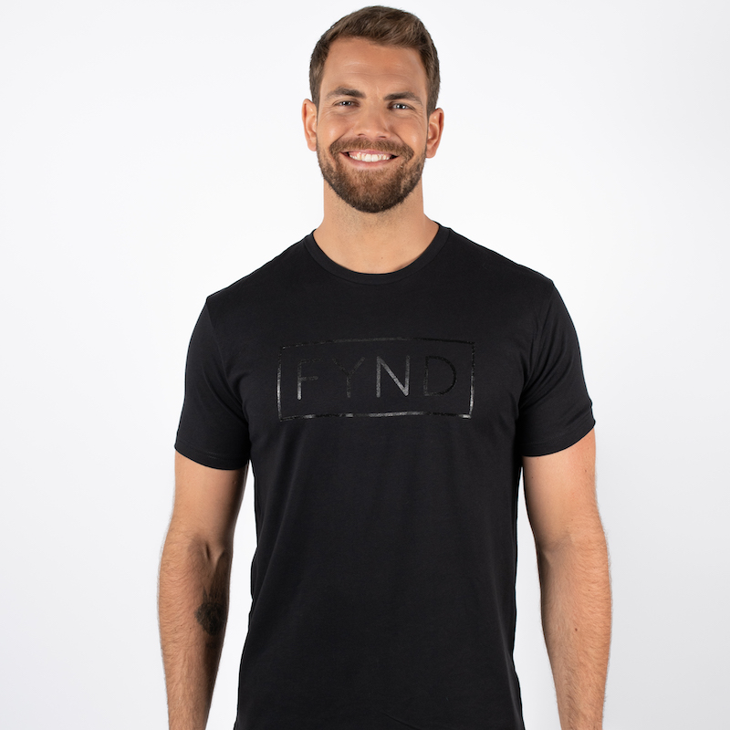 Mann avbildet forfra iført en sort t-skjorte med teksten FYND skrevet i et rektangel i sort midt på brystet