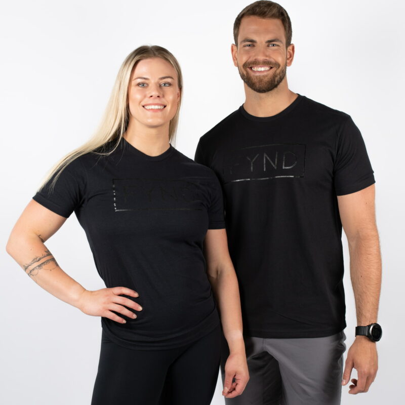 Mann og kvinne avbildet forfra, iført sorte t-skjorter. Med teksten FYND skrevet i et rektangel i sort midt på brystet.