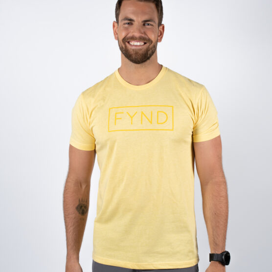 Mann avbildet forfra iført en lys gul t-skjorte, med teksten FYND skrevet i et rektangel med gul skrift midt på brystet