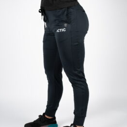 actic joggebukse, Kvinne avbildet fra siden iført sort langbukse med åpne lommer, snøring i livet og ACTIC skrevet i hvit øverst på høyre lår