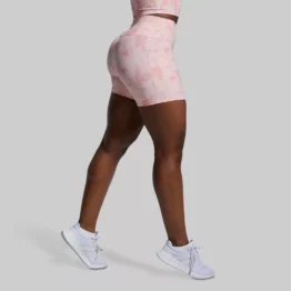 Shorts med høyt liv. Beina til en kvinne som står med siden mot kameraet. Hun har på seg en rosa spraglete All or Nothing shorts. Shortsen er ribbestrikket og den er høy i livet.
