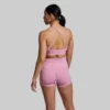En kvinne som står med ryggen mot kameraet og har på seg en Exhale rosa sports-bh og en rosa New Heights shorts. Sports-bh'en har to stropper på hver side. To av stroppene krysser hverandre bak på ryggen.