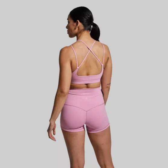 En kvinne som står med ryggen mot kameraet og har på seg en Exhale rosa sports-bh og en rosa New Heights shorts. Sports-bh'en har to stropper på hver side. To av stroppene krysser hverandre bak på ryggen.