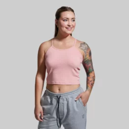 En kvinne som står vendt mot kameraet. Hun har på seg en Keep it easy rosa topp og en grå joggebukse. Toppen er ribbestrikket og har en tynn stropp over hver skulder.