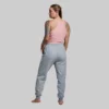 En kvinne som står med ryggen mot kameraet. Hun har på seg en Keep it easy rosa topp og en grå joggebukse. Toppen er ribbestrikket og har en tynn stropp over hver skulder.