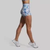 Booty short, treningsshorts. Beina til en kvinne som har på seg en New Heights shorts. Shortsen har et mønster i fargene blå, hvit, rosa, sort, brun og gul. Den er høy i livet.