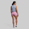 Kvinne som står med ryggen mot kameraet. Hun har på seg en Subtle flex tank topp og en rosa New Heights shorts. Toppen har et mønster i blå, hvit, rosa, sort, brun og gul.