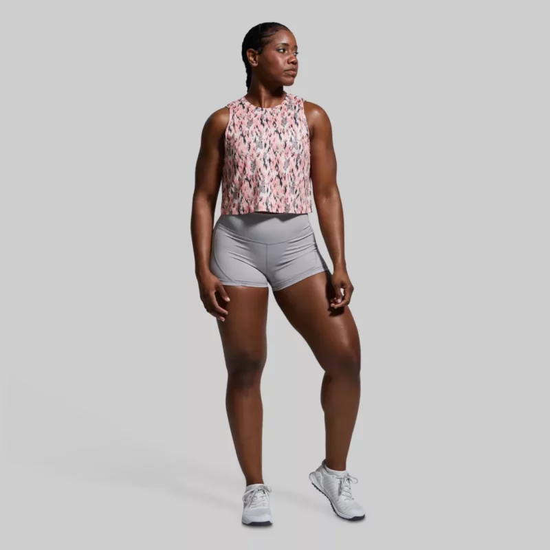 Kvinne som står vendt mot kameraet. Hun har på seg en Subtle flex tank topp og en grå shorts. Toppen har et mønster i rosa, sort og kremhvit.