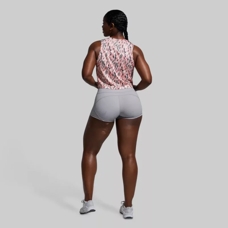 Kvinne som står med ryggen mot kameraet. Hun har på seg en Subtle flex tank topp og en grå shorts. Toppen har et mønster i rosa, sort og kremhvit.