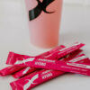 Bilde av rosa porsjonspakker av sportsdrikken Hydro Raspberry Lemonade på en benk.