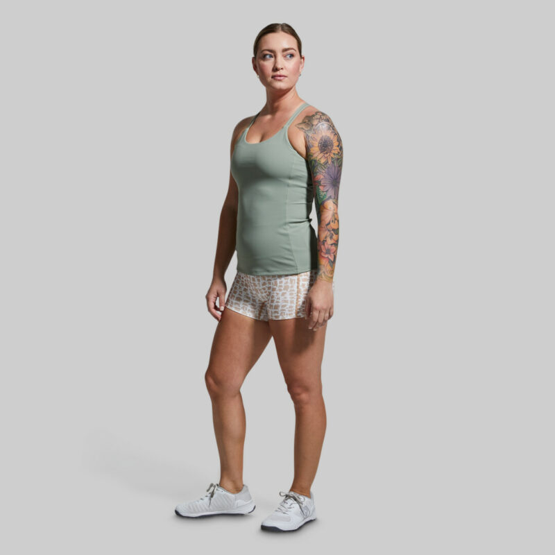 Kvinne med hvit og lysebrun mønstrete trenings-shorts med lomme på én side.