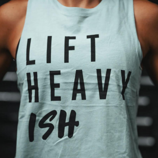 Lift Heavy Ish Tank topp til styrketrening. Kvinne iført turkis treningstopp med sort skrift foran. Teksten sier "Lift Heavy Ish".