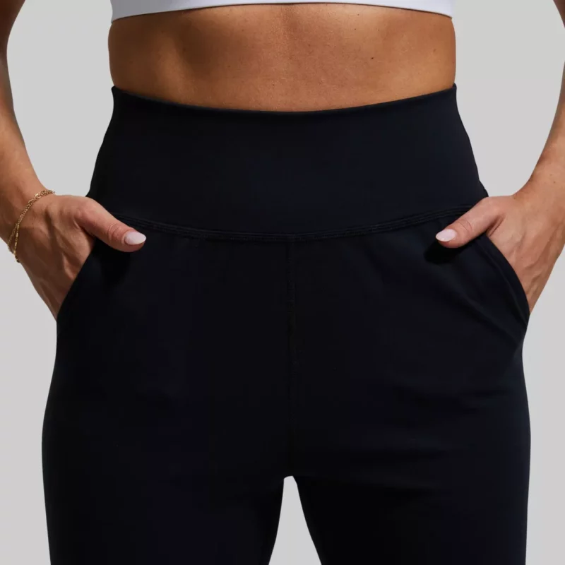 Kvinne i sort joggebukse med lommer. Buksen er høy i livet.