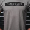 Mann iført lysebrun/grå t-skjorte med tekst foran. Teksten sier "Cardio Sucks".