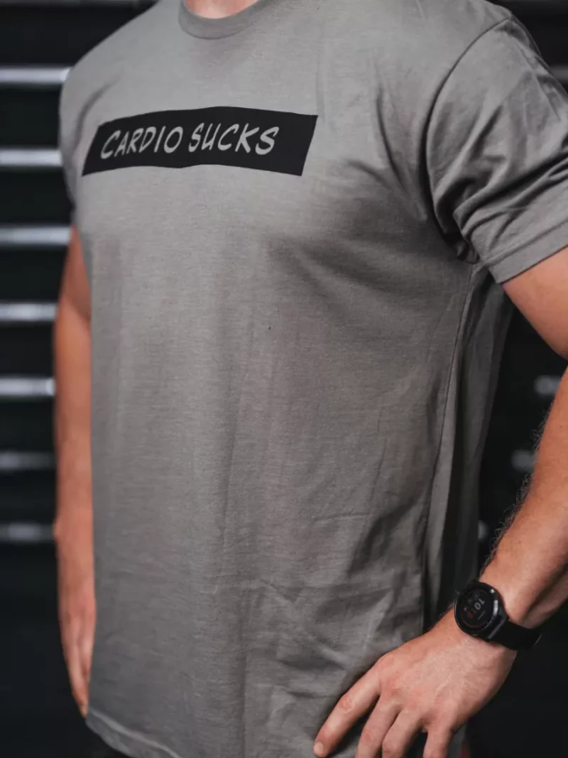 Mann iført lysebrun/grå t-skjorte med tekst foran. Teksten sier "Cardio Sucks".