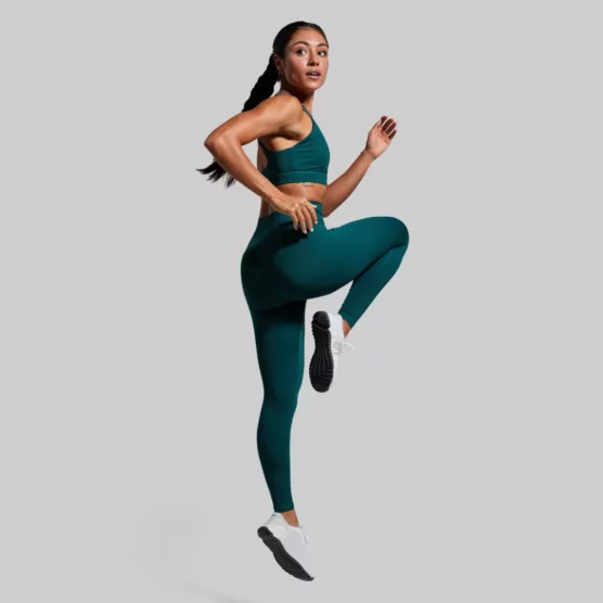 Kvinne med mørkegrønn treningstights. Tightsen er høy i livet.