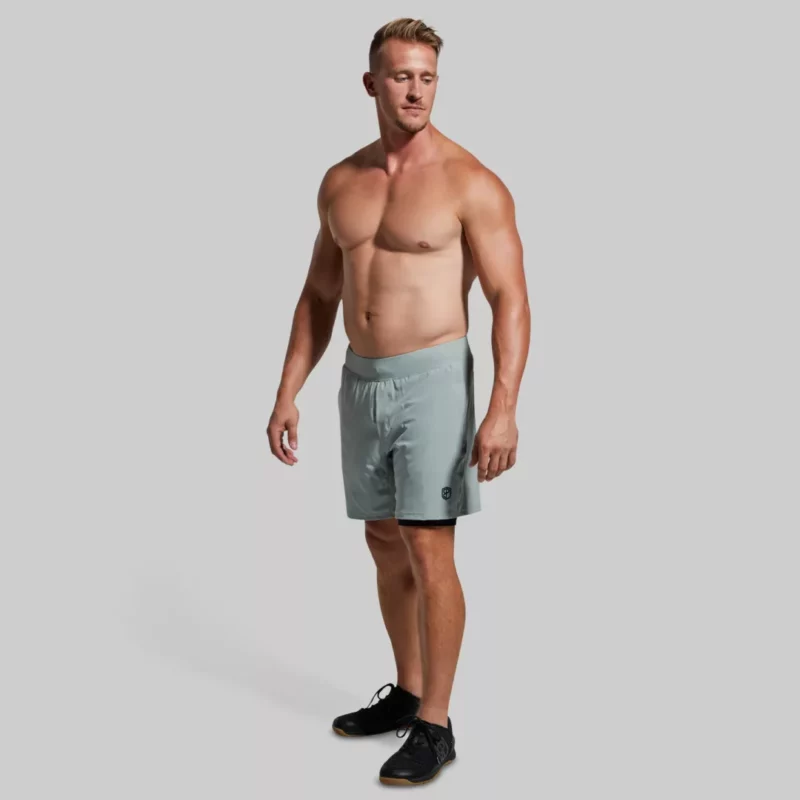 Mann med lys grå trenings-short med lommer. Shortsen har innertights med lomme på én side.