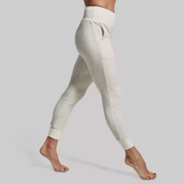Women's Cloud Jogger (Heather Oatmeal) Joggebukse dame Kvinne iført en dus hvit joggebukse. Buksen har lommer og strikk nederst på beina. Buksen er høy i livet.