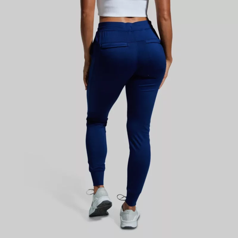 Kvinne med mørkeblå joggebukse med lommer foran og bak. Buksen har knyting i livet.
