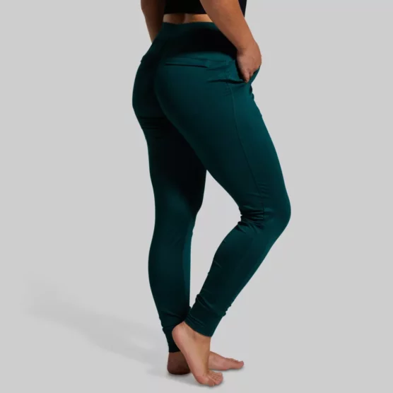 Kvinne med mørkegrønn joggebukse med lommer foran og bak. Buksen har knyting i livet.